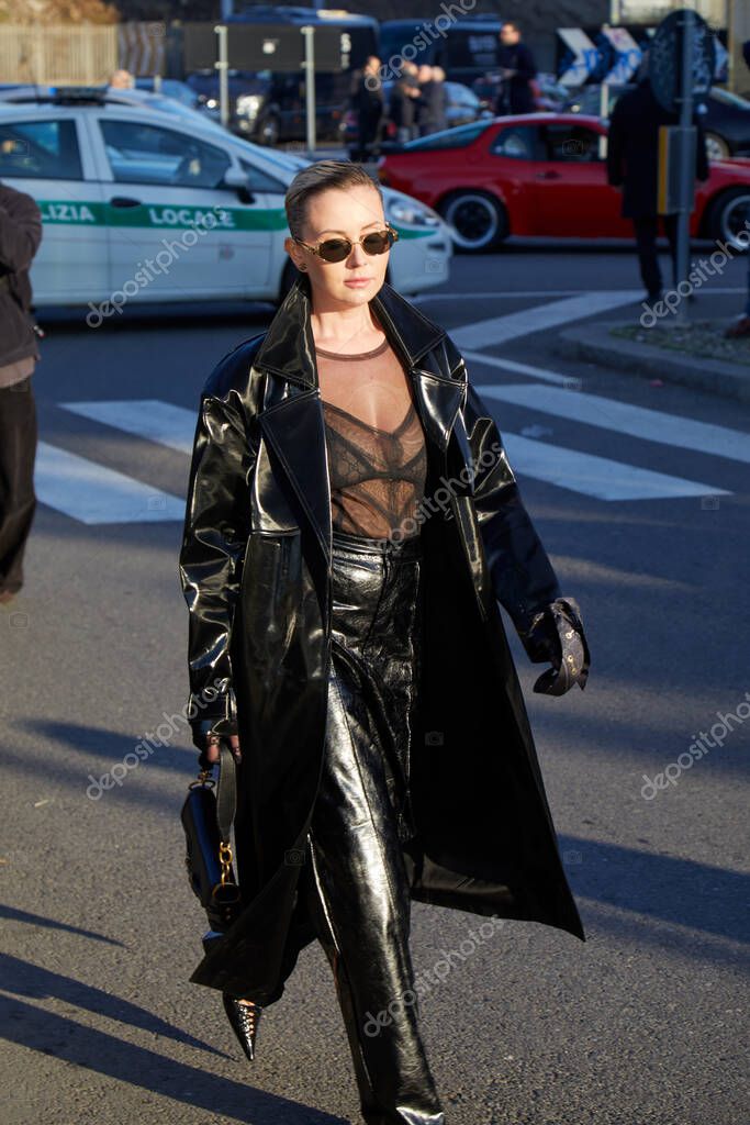 MILAN, ITALY - JANUARY 12 , 2024: Woman with black leather trench coat and trousers before Gucci fashion show, Milan Fashion Week street styl
