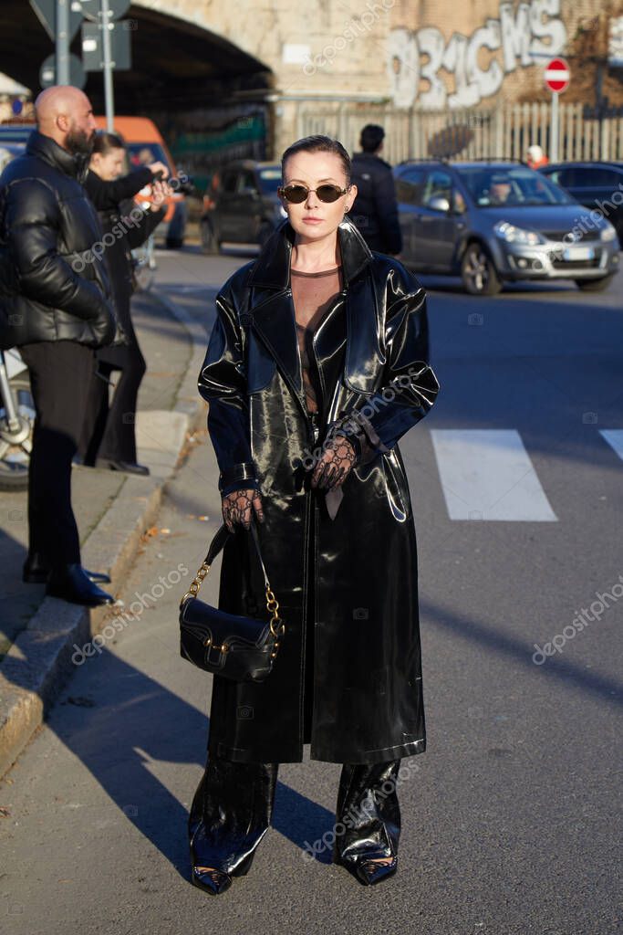 MILAN, ITALY - JANUARY 12 , 2024: Woman with black leather trench coat and trousers before Gucci fashion show, Milan Fashion Week street styl