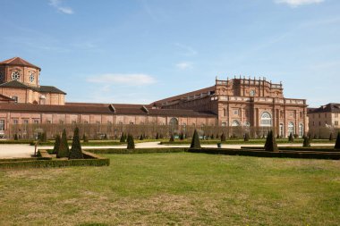 VENARIA GERÇEK, İTALYA - 29 Mart 2023: Reggia di Venaria Şatosu mimarisi ve piramit çitleri ile bahar güneşinin altında park