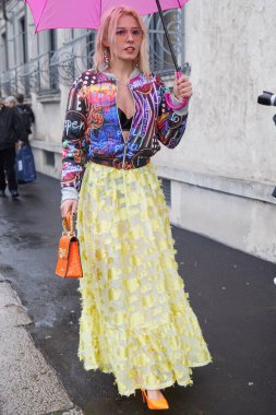 MILAN, İtalya - 22 Şubat 2024: Sarı etekli, turuncu çantalı ve neon tasarım bombacı ceketli kadın Prada defilesinden önce, Milan Moda Haftası tarzı