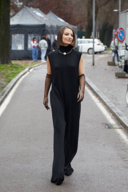 MILAN, İtalya - 23 Şubat 2024: Sportmax defilesinden önce siyah tulumlu ve şeffaf eldivenli kadın, Milan Moda Haftası tarzı