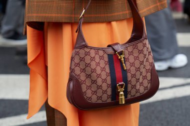 MILAN, İtalya - 23 Şubat 2024: Burgundy Gucci çanta ve turuncu etekli kadın Gucci defilesinden önce, Milan Moda Haftası tarzı