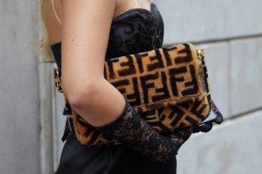 MILAN, İtalya - 25 Şubat 2024: Bej ve kahverengi Fendi kürk çantalı ve siyah dantel eldivenli kadın Giorgio Armani defilesinden önce, Milan Moda Haftası tarzı