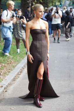 MILAN, ITALY - SEPTEMBER 20, 2024: Caro Daur with brown dress and burgundy boots before Gucci fashion show, Milan street style clipart