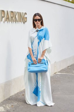 MİLAN, İTALYA 21 Eylül 2024 Ferragamo defilesinden önce beyaz ve mavi elbiseli ve çantalı kadın, Milano sokak tarzı