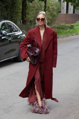 MİLAN, İTALYA 21 Eylül 2024: koyu kırmızı paltolu ve tüylü Leonie Hanne Ferragamo defilesinden önce, Milan sokak stili
