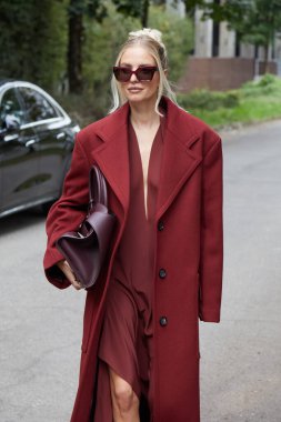 MİLAN, İTALYA 21 Eylül 2024: koyu kırmızı ceketli ve güneş gözlüklü Leonie Hanne Ferragamo defilesinden önce, Milano sokak tarzı