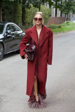 MİLAN, İTALYA 21 Eylül 2024: koyu kırmızı paltolu ve tüylü Leonie Hanne Ferragamo defilesinden önce, Milan sokak stili