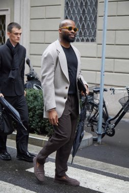 MİLAN, İTALYA 20 HAZİRAN 2025: bej ceketli, kahverengi pantolonlu ve şemsiyeli adam Giorgio Armani defilesinden önce, Milan Moda Haftası tarzı