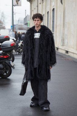 MİLAN, İTALYA 19 Ocak 2025: Prada defilesinden önce siyah kürklü ve siyah kot pantolonlu adam, Milan Moda Haftası tarzı