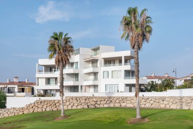Amarilla Golf, San Miguel de Abona, Tenerife, Canary Islands, Spain - October 19, 2021: views towards a Mediterranean-style residential building surrounded by the green golf course and tall palm trees