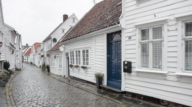 Stavanger, Norveç - 3 Ağustos 2018: Yağmurun altında parlayan kaldırımlı sokakları ile Gamble Stavanger olarak bilinen eski kasaba 18. yüzyıla dayanan geleneksel beyaz ahşap evlerle aynı hizaya geldi.