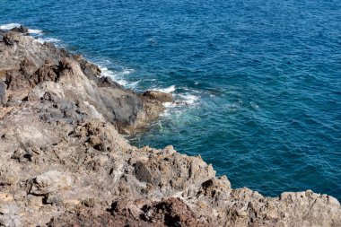 Kristal mavi sular engebeli, yıpranmış kıyılara karşı küçük dalgalar halinde kırılıyor, güzel doğa sahneleri ilham verici tatil atmosferleri, yaz tatilleri maceraları veya kıyı yaşamının huzurlu atmosferi