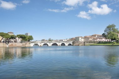 Kanal kenarındaki küçük İtalyan kasabasında güzel bir gün. Roma mühendisliğinin M.Ö. 1. yüzyıla dayanan simgesel bir sembolü olan Tiberius Köprüsü 'nün yanındaki tarihi köprü. Rimini, İtalya.