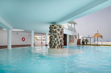 Ada Village Heights, Costa Adeje, Tenerife, Kanarya Adaları, İspanya - 17 Mart 2024: Aile dostu tatil köyünde kısmen örtülü yüzme havuzu, rahat ve doğal mimari detaylar sergileniyor
