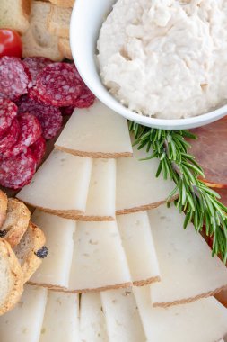 Ortak bir aşçılık deneyimi için hazırlanmış bir şarküteri tahtasındaki dilimlenmiş peynir ve kurutulmuş etler, İspanyol salamı, taze tost, kremalı sos ve kurutulmuş Manchego peyniri.