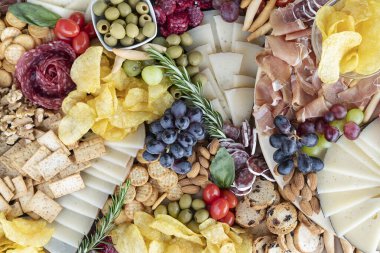 Flat charcuterie tahtası çeşitli soğuk pirzola çeşitleri ile cömertçe düzenlenmiş, kraker, kraker ve ekmek, fındık ve zeytin, cips ve otlar, çeşitli dokular ve tatlar için