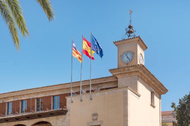 Consulado del Mar, Palma de Mallorca, Balearic Adaları, İspanya - 25 Haziran 2024: saat kulesi ve üç bayrak: İspanyol, Avrupa Birliği ve Balearic bölgesel bayrağı deniz hukuku kurumunun tepesinde