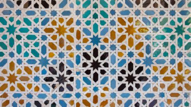 Karmaşık geometrik desenlere sahip Endülüs seramik mozaiği, birbirine kenetlenmiş yıldız şekilleri ve mavi, yeşil ve sarı renkli çokgenler, Sevilla, İspanya 'da simetrik bir kompozisyon oluşturur.