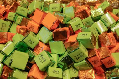Viyana, Avusturya - 16 Mayıs 2025: Parlak yeşil, turuncu ve bronz folyolu Lindt Nougat ya da Lindt Knusper Nougat Creme etiketli bireysel paketlenmiş çikolataların renkli çeşitleri, premium şekerlemeler