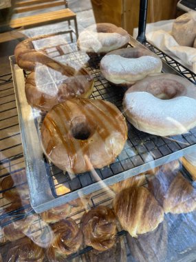 Tatlı çörekler, jöleli çörekler, pişmiş yiyecekler. Donut üretimi. Çörekler kızartılmış, jöleli ve bir donut fırınında raflara serilmiş..