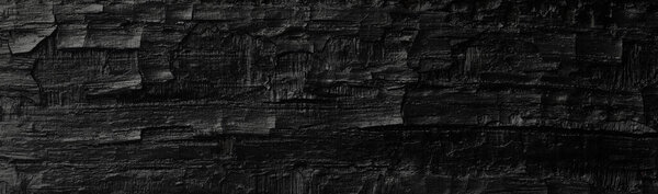 Dark black background of rough burnt wood, soot, and ash. Burn texture.