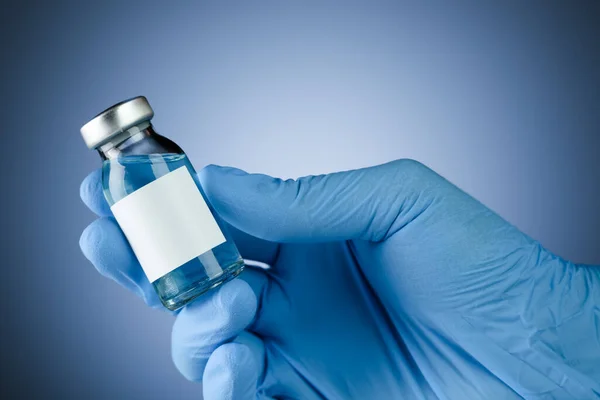 携带带有空白空白空白文字空白疫苗瓶的蓝色医用手套 带有文字版权空间的卫生保健概念 — 图库照片