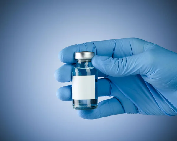 携带带有空白空白空白文字空白疫苗瓶的蓝色医用手套 带有文字版权空间的卫生保健概念 — 图库照片