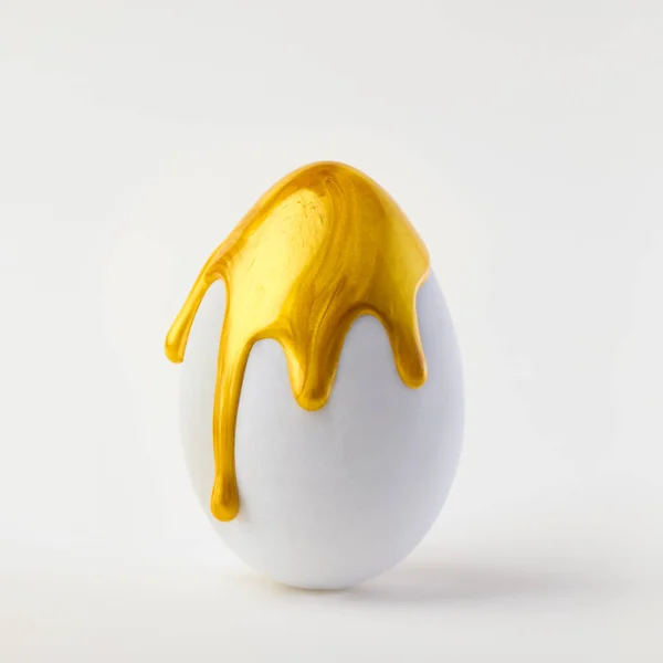 Único Ovo Branco Salpicado Pingando Com Tinta Dourada Brilhante Simboliza — Fotografia de Stock
