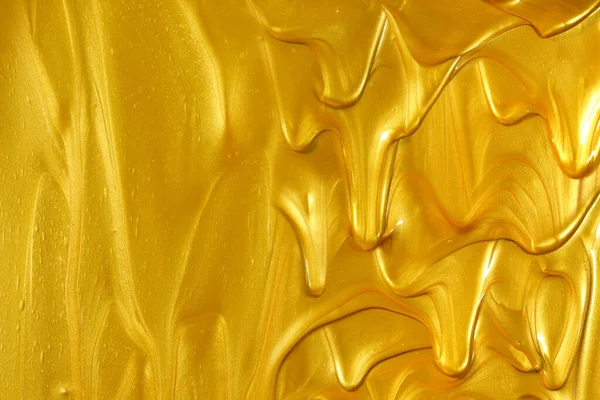 光沢のある金属製の金の塗料が流れると空のコピースペースと黄金の背景を作る下方に滴下 — ストック写真