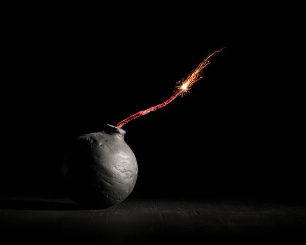 火のついた丸みを帯びた黒い爆弾は火花で燃えます または危険な暴力を象徴する爆弾を爆発させようとしている — ストック写真