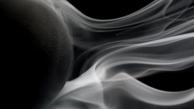 Yatay duman kıvrılıyor ve boş bir uzayın etrafında yumuşak ruhani dalgalar süzülüyor. Siyah arkaplanda gerçek duman.