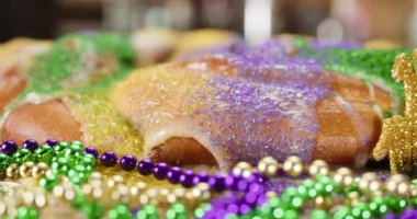 Ev yapımı Mardi Gras kral pastası. Sarı, altın, yeşil ve mor şeker serpiştirilmiş. Parlak Mardi Gras boncukları ve parlak altın metinlerle çevrili bu geleneği kutlamak için Mutlu Mardi Gras.