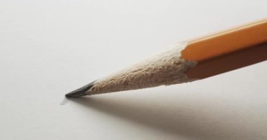 Keskin grafit uçlu sarı kalem düz beyaz kağıda basit kıvrımlı bir çizgi çiziyor. Keskin kurşunun ardından kağıda dalgalı bir karalama yazarak bir kalem çizimi başlatıyorum..