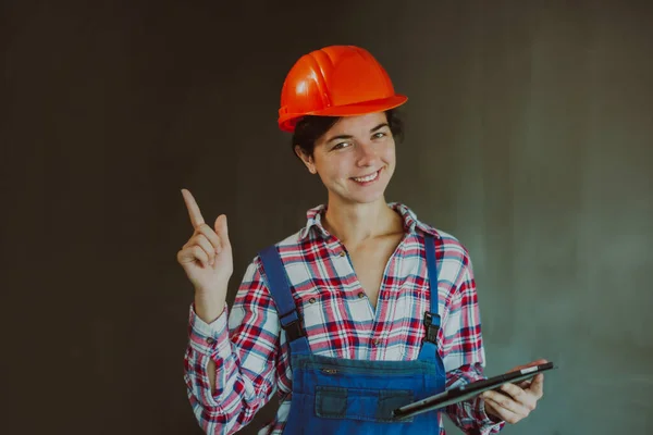 笑顔の幸せな女性ビルダーは コンクリートの壁に指をポイントし 新しい建物でプロジェクトをチェックします 男性の職業や平等における女性の仕事の概念は — ストック写真