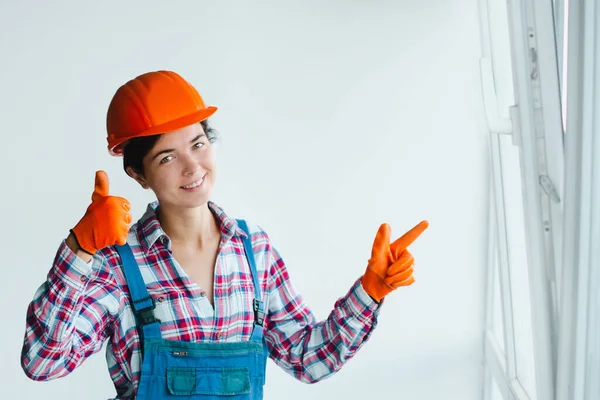 女性建設労働者は金属プラスチックの窓に指を向けます 男性の職業や平等における女性の仕事の概念は — ストック写真