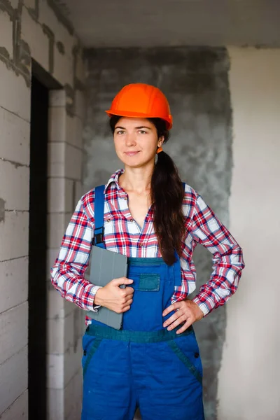 Construction maintenance engineer woman in uniform and protective helmet inspecting and checking repair building with help of tablet. Industry, engineer, construction concept.