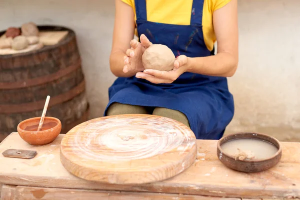 hands of craft woman working with clay lump in pottery studio in village