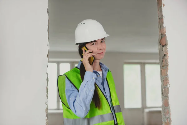 foreman woman consults clients on mobile phone. Inspector or Safety Supervisor in construction site. woman in man construction profession
