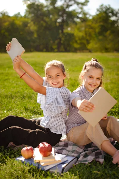 两个兴奋的女孩在绿地公园看书 手里拿着生态书籍的女孩 封面设计模型 — 图库照片