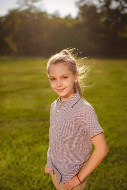 Çocuk kız, ilkbaharda yeşil çayırlarda ya da parkta rüzgarla yürüyor.