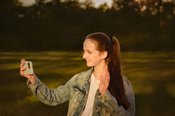 Счастливая Девочка Подросток Здоровается Машет Рукой Камеру Смартфона Парке Жестикулирует — стоковое фото