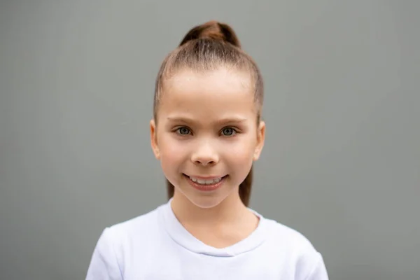 Gri Arka Planda Uzun Kuyruklu Beyaz Kazaklı Gülümseyen Küçük Kızın — Stok fotoğraf
