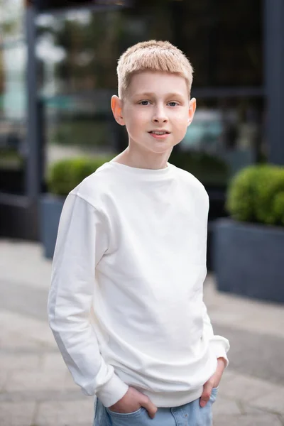 通りを歩いて白いパーカーのスタイリッシュな学校の少年 子供服をモックアップ — ストック写真