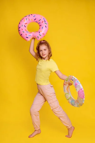 full height girl in yellow T-shirt mock up juggle with two inflatable rings in hands isolated over yellow background