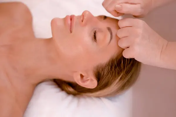 forehead anti wrinkle massage for woman in beauty salon. female getting face lifting massage