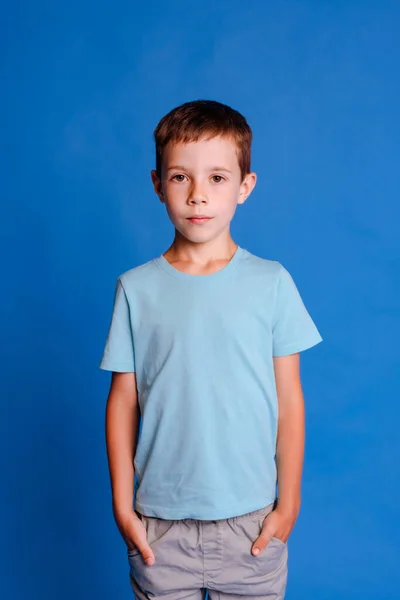 Allvarlig Skolpojke Blå Mockup Shirt Tittar Kameran Ljusblå Studio Bakgrund — Stockfoto