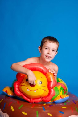 Çocuk, açık mavi stüdyo arka planında yüzme havuzu konseptinde oynuyor.