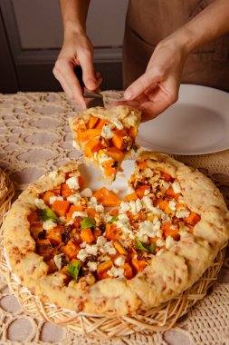 Ev yapımı fırın - balkabağı açık turta, kadın ellerinde pastayı kesme