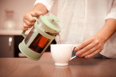 Kadın beyaz fincana çay dolduruyor. Yatmadan önce akşam ritüeli